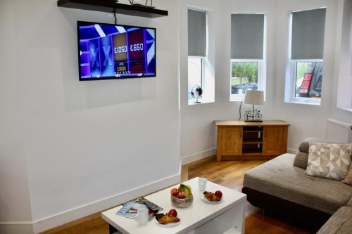 a living room with a couch and a tv on the wall at Holiday Home Hot Tub & Sauna in Bournemouth