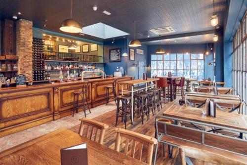 a restaurant with wooden tables and chairs and a bar at Large Bedroom in beautiful house in London