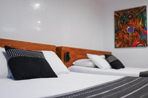two beds with black and white pillows in a room at Casa de Arte Hotel Boutique in Oaxaca City