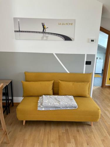 a yellow couch in a living room with a painting on the wall at La La Home in Avezzano