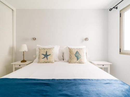 1 dormitorio con 1 cama blanca con sábanas y almohadas azules en Avatar Auditorio, en Las Palmas de Gran Canaria
