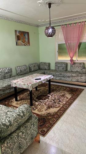 a living room with a table and a couch at شقق تادارت Logements Taddart in Khemisset