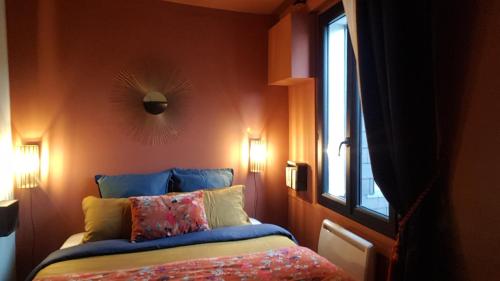 une chambre avec un lit avec des oreillers et une fenêtre dans l'établissement le velours des gantiers, confort et hospitalité en plein centre historique, à Rouen