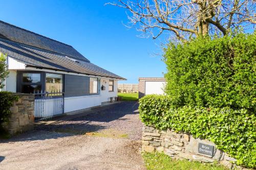 a house with a hedge next to a building at Bryn Derwen in Valley