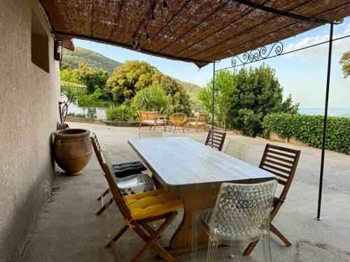 een houten tafel en stoelen op een patio bij Maison à la campagne. in Sollacaro