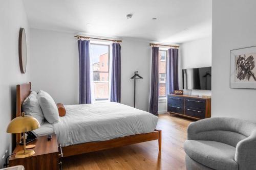 a bedroom with a bed and a chair and a television at King Bed, Fiber Internet, Heart of Bangor, 50 Roku TV, Room # 208 in Bangor
