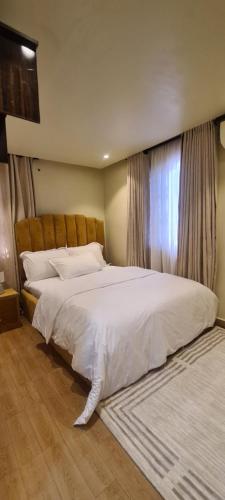 Un dormitorio con una gran cama blanca y una ventana en Mindyourbusiness villa en Abuja