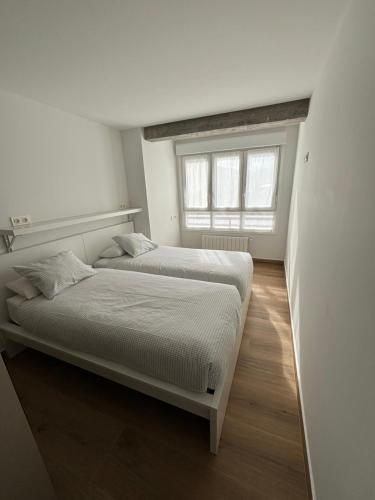 two beds in a white room with a window at Apartamento Elkano 1 in Hernani