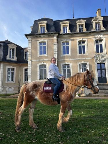 a man riding a horse in front of a building at Suite Bien être du Château de la Bouchatte in Chazemais