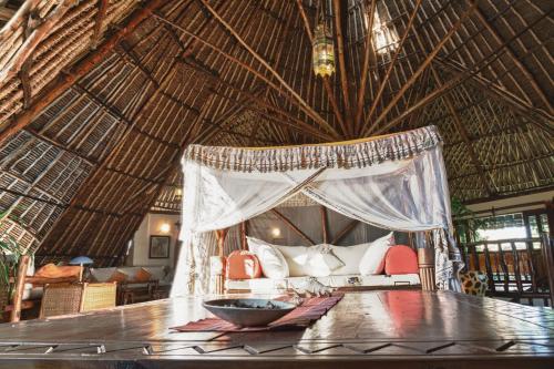 a room with a table and a bed in a straw hut at Diani Villa in Diani Beach