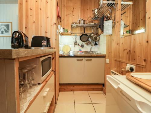 a small kitchen with wooden walls and a sink at Lake Lodge Studio in Bowness-on-Windermere