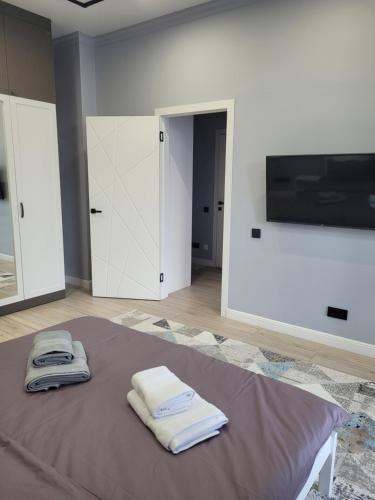 a bedroom with two towels on a bed with a flat screen tv at ЖК Apple City 1 СПАЛЬНЯ in Prigorodnyy