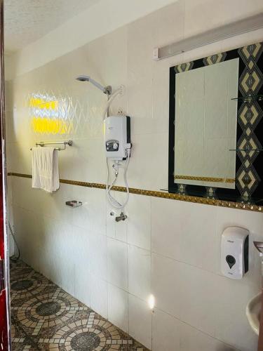 łazienka z prysznicem i lustrem na ścianie w obiekcie Gator's Hotel Kasese w Kasese