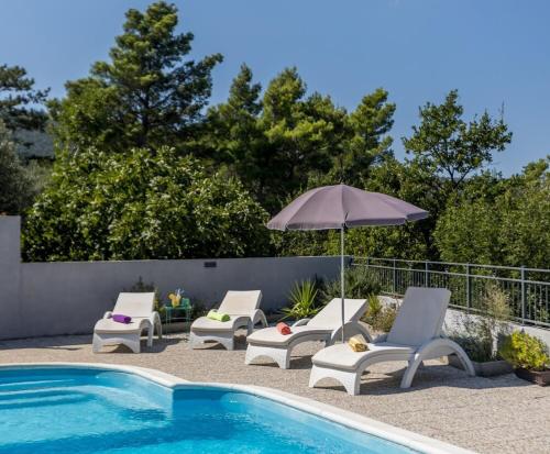 a group of chairs and an umbrella next to a swimming pool at Villa Almond near Omis, private pool in Tugare