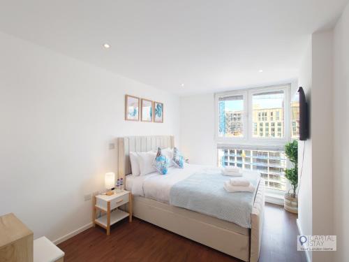a white bedroom with a bed and a window at Deluxe Two Bed Apartment by London ExCeL & O2 in London