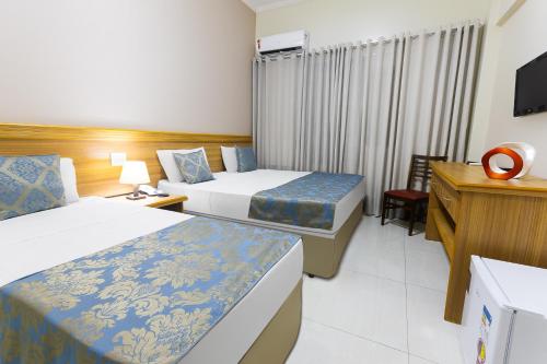 a hotel room with two beds and a television at Hotel Dan Inn Express Ribeirão Preto in Ribeirão Preto