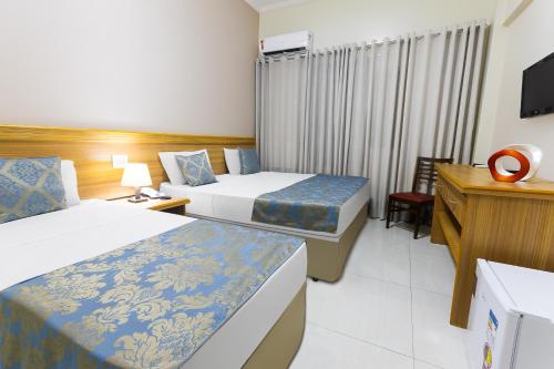 a hotel room with two beds and a television at Hotel Dan Inn Express Ribeirão Preto By Nacional Inn in Ribeirão Preto