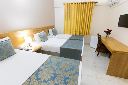 a hotel room with two beds and a desk at Hotel Dan Inn Express Ribeirão Preto in Ribeirão Preto
