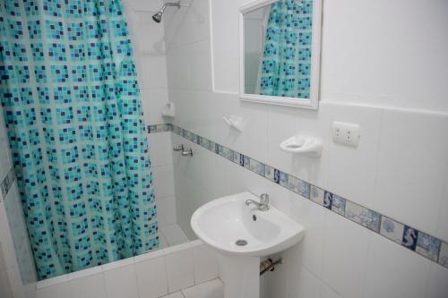 a bathroom with a sink and a blue shower curtain at Casa mar surfhouse in Punta Hermosa