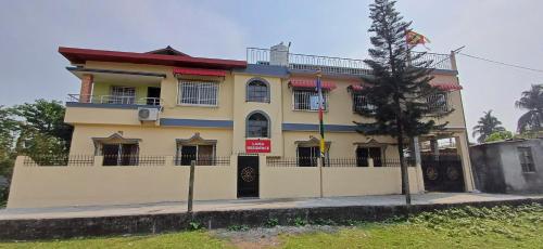 un bâtiment jaune avec un arbre devant lui dans l'établissement Lama Residency, à Siliguri