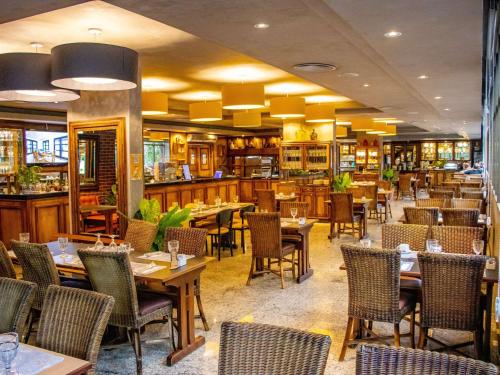 a restaurant with tables and chairs in a room at Manhattan Porto Alegre by Mercure in Porto Alegre