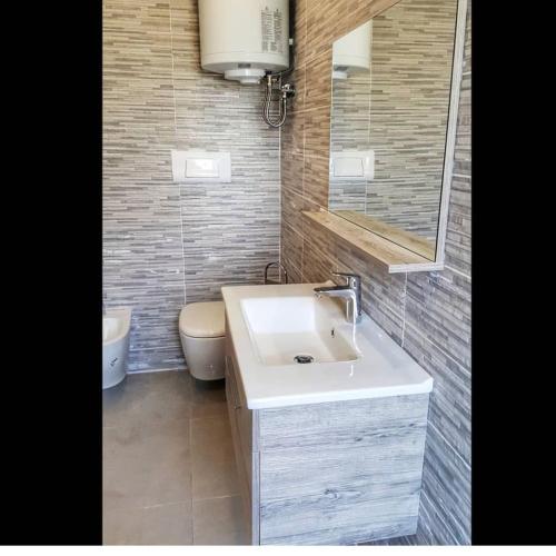 La salle de bains est pourvue d'un lavabo blanc et de toilettes. dans l'établissement Sunrise Comforts, à Tirana