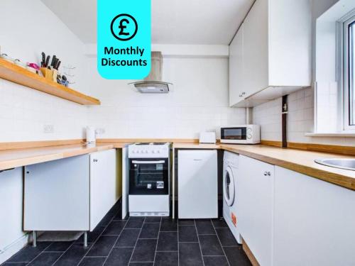 a kitchen with white cabinets and a counter top at Lovely 2 Bed Apartment near the Sea in Lancing