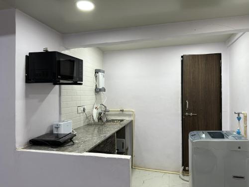 a bathroom with a sink and a tv on the wall at Ravish Apartment, Juhu in Mumbai