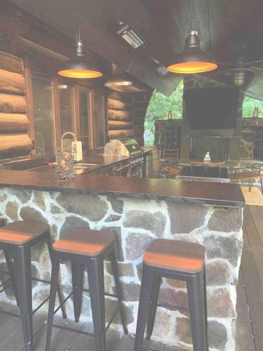 a bar with two stools and a stone wall at The Kresge Kabin - Authentic Grand Log Cabin. in Vermont Ventures
