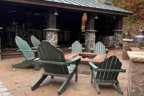 four green chairs and a table on a patio at The Kresge Kabin - Authentic Grand Log Cabin. in Vermont Ventures