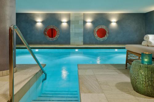 a swimming pool in a hotel room with a table and a couch at Hotel Duene in Rantum