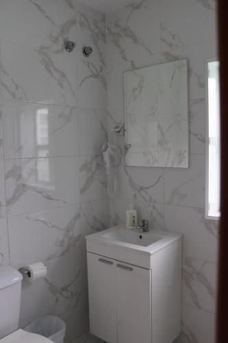 a white bathroom with a sink and a mirror at Pension La Corredera in Tui