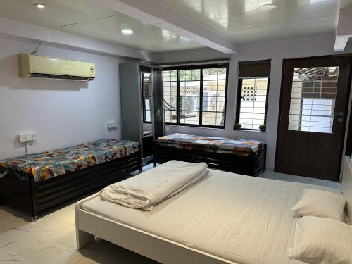 a bedroom with two beds and two windows at Ravish Apartment, Juhu in Mumbai
