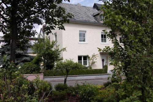 una casa blanca con árboles y arbustos delante de ella en Ferienhaus in Trittenheim mit Privatem Garten en Trittenheim