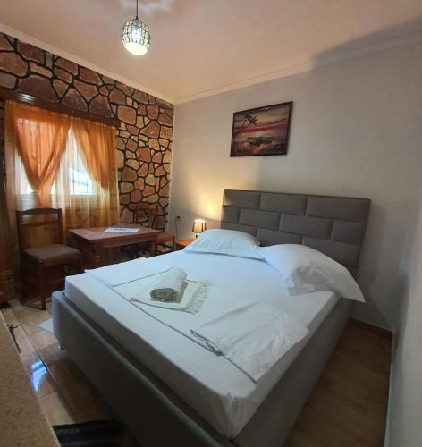 a bedroom with a large white bed and a table at Vokopola Villa in Sarandë