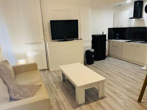 een woonkamer met een bank, een tafel en een tv bij Le Petit Paradis : 2-4 pers WIFI in Boulogne-sur-Mer