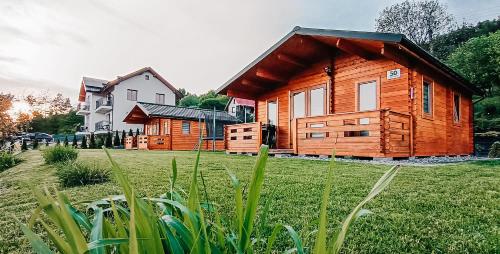 a wooden cabin in a field with a house at Domki Na Stoku Laworty in Ustrzyki Dolne