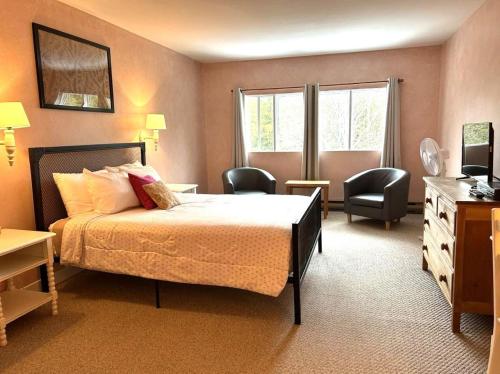 a bedroom with a bed and two chairs in it at Auberge Les Sources in La Malbaie