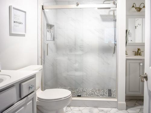 a white bathroom with a shower and a toilet at Private Mod Boho Chic Retreat Mins DTWN Beach in Saint Augustine