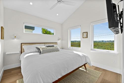 een witte slaapkamer met een bed en 2 ramen bij 194 Riberia - Downtown Waterfront Luxury Home in St. Augustine