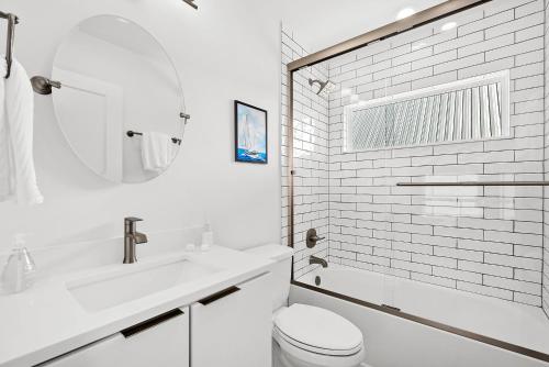a white bathroom with a toilet and a sink at 200 Riberia - Downtown Waterfront Luxury Home in St. Augustine