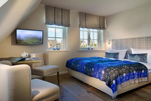 a bedroom with a bed and a desk and windows at Hotel Duene in Rantum