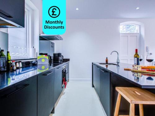 een keuken met zwarte kasten en een aanrecht bij Charming 1BR Apartment in a gated complex and a short walk from Queens Park Tube in Londen