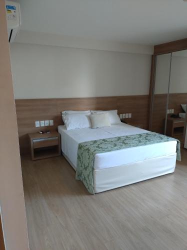 ペドラ・アズールにあるVista Azul Apart Hotel - Vista Pedra Azulの大きな白いベッドとテーブルのある寝室