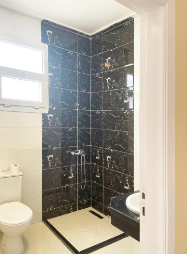 a bathroom with a black tiled shower with a toilet at Karima House in Luxor