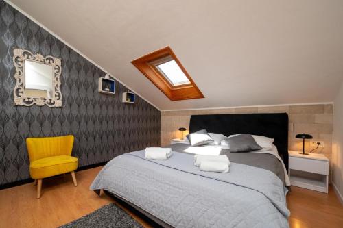 a bedroom with a large bed and a yellow chair at Villa Jidro in Trogir