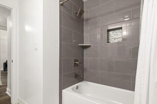 a bathroom with a white tub and a gray tile wall at Island Suite - Walk to Downtown! in Saint Augustine