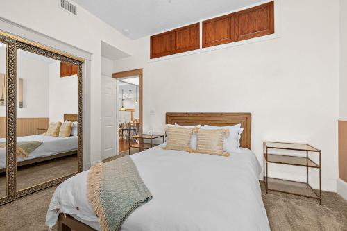 um quarto com uma cama branca e um espelho em The Ray - 2nd Floor Historic Condo- Minutes Walk to Downtown em Saint Augustine