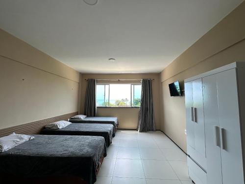 een hotelkamer met 3 bedden en een raam bij Apartamento no Centro do Cumbuco in Cumbuco