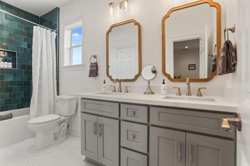uma casa de banho com 2 lavatórios, um WC e um espelho. em Luxury New 3BD Home with Parking and Private Yard em Nova Orleans